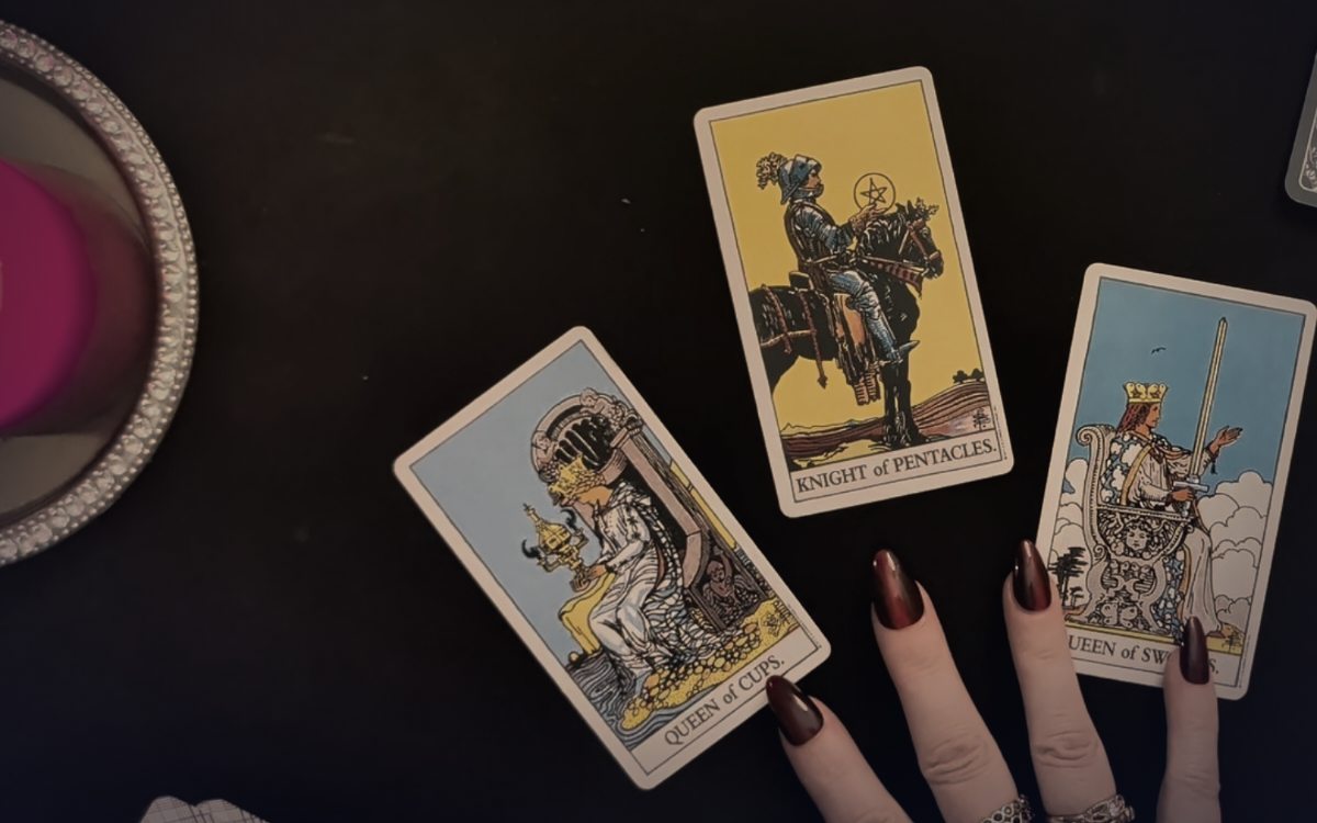 Tarotkarte Königin der Kelche neben einer brennenden Kerze