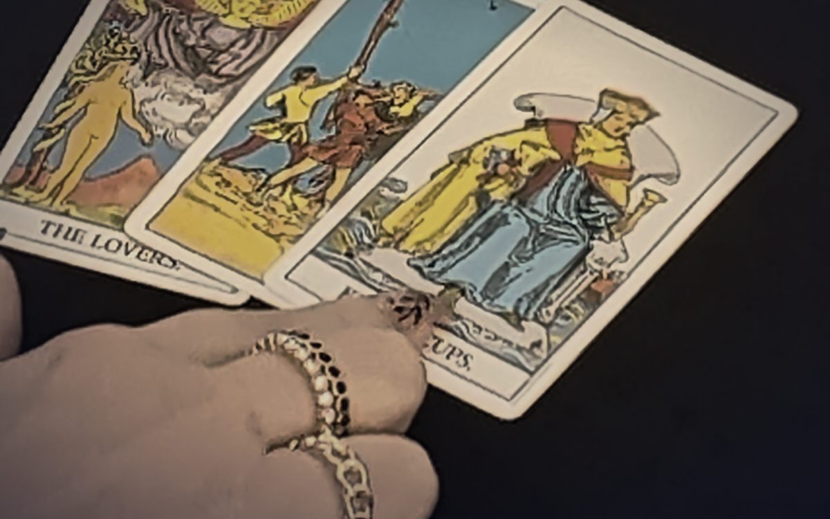 Hand auf der Tarotkarte Die Liebenden