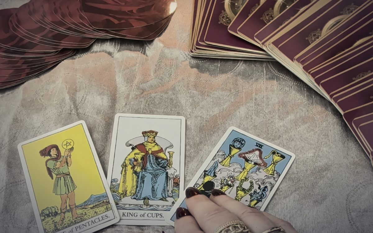 Rosen, eine brennende Kerze und drei Tarotkarten auf einem dunklen Tisch